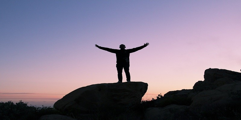 man with open arms on mountain