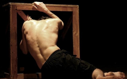 TOURNEE Festival Theatrical scene: man bent over a piece of wood